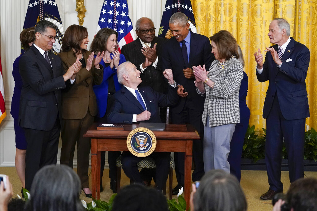 President Joe Biden looks to former President Barack Obama after signing an executive order during and event about the Affordable Care Act, in the East Room of the White House in Washington, Tuesday, April 5, 2022. Also seen are Health and Human Services Secretary Xavier Becerra Vice President Kamala Harris, Rep. Angie Craig, D-Minn., House Majority Whip James Clyburn, D-S.C., and House Speaker Nancy Pelosi of Calif., and Sen. Tom Carper, D-Del. (AP Photo/Carolyn Kaster)