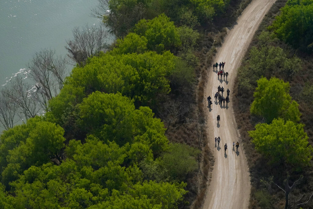 Migrants walk on a dirt road after crossing the U.S.-Mexico border, Tuesday, March 23, 2021, in Mission, Texas. (AP Photo/Julio Cortez)