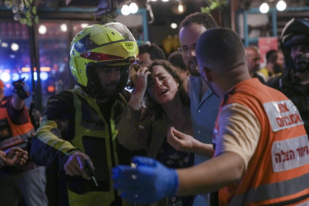 A woman reacts at the scene of a shooting attack In Tel Aviv, Israel, Thursday, April 7, 2022. Israeli health officials say two people were killed and at least eight others wounded in a shooting in central Tel Aviv. The shooting on Thursday evening, the fourth attack in recent weeks, occurred in a crowded area with several bars and restaurants. (AP Photo/Ariel Schalit). (AP Photo/Ariel Schalit)