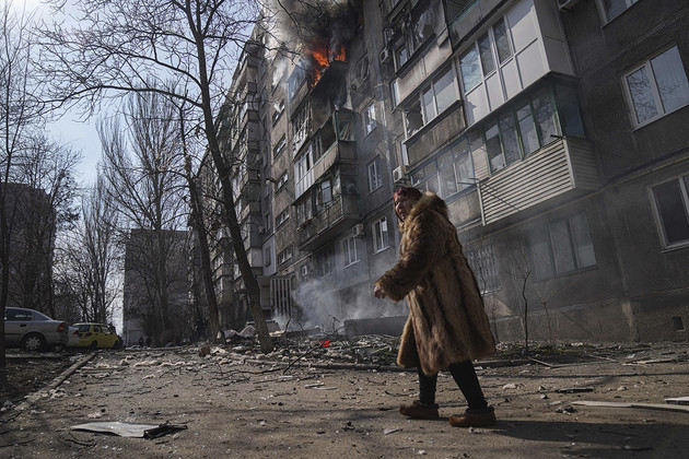 A person walks past a burning apartment building after shelling in Mariupol, Ukraine. | Evgeniy Maloletka/AP Photo