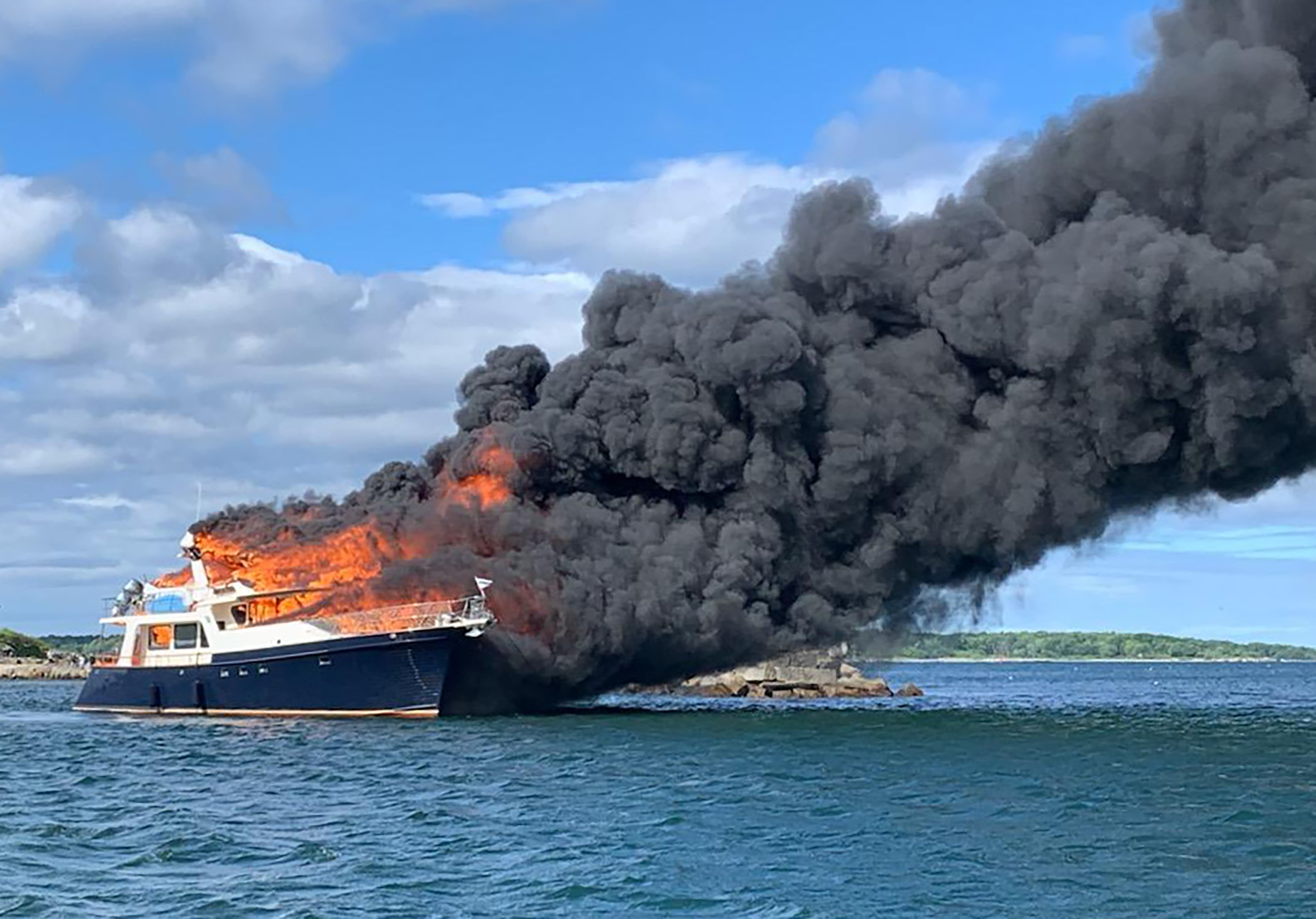 This image provided by New Hampshire State Police shows a yacht burning on the Piscataqua River in New Castle, N.H., Saturday, June 18, 2022. (New Hampshire State Police via AP)