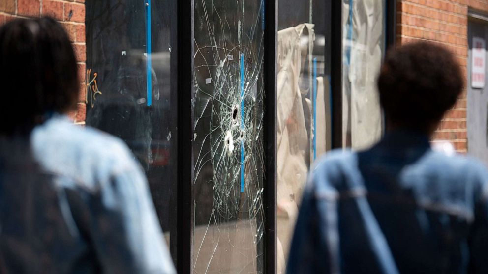 PHOTO: Pedestrians walk past bullet holes in the window of a store front on South Street in Philadelphia, June 5, 2022.