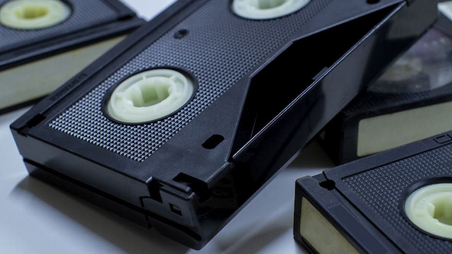 A collection of VHS tapes are stacked on a surface