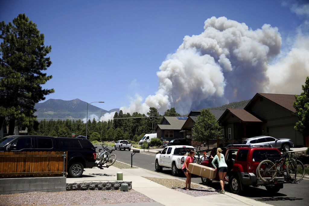 People evacuate their home as the Pipeline Fire burns in the mountains above Flagstaff, Ariz., Sunday, June 12, 2022. The fire has forced the evacuation of several hundred homes. (Jake Bacon/Arizona Daily Sun via AP)