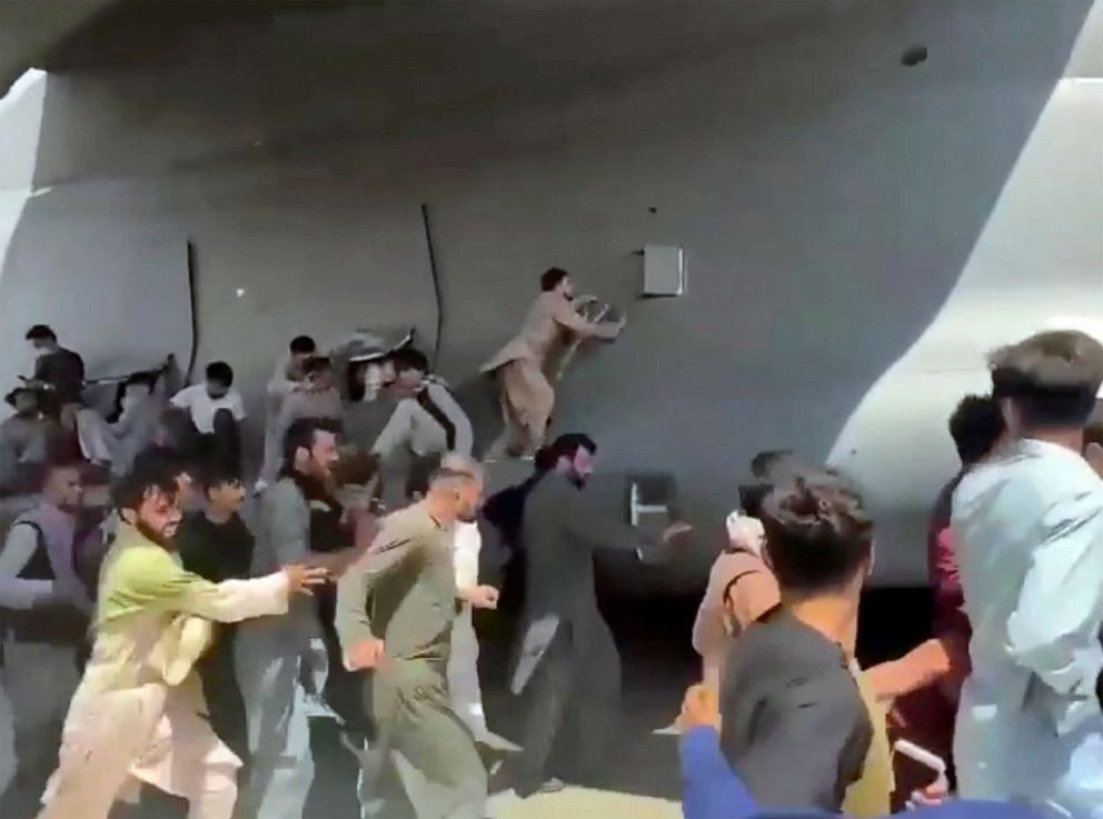 PHOTO: Hundreds of people run alongside a U.S. Air Force C-17 transport plane, some climbing on the plane, as it moves down a runway of the international airport, in Kabul, Afghanistan, Aug.16. 2021.