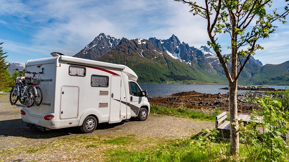 Recreational vehicle next to river, mountains