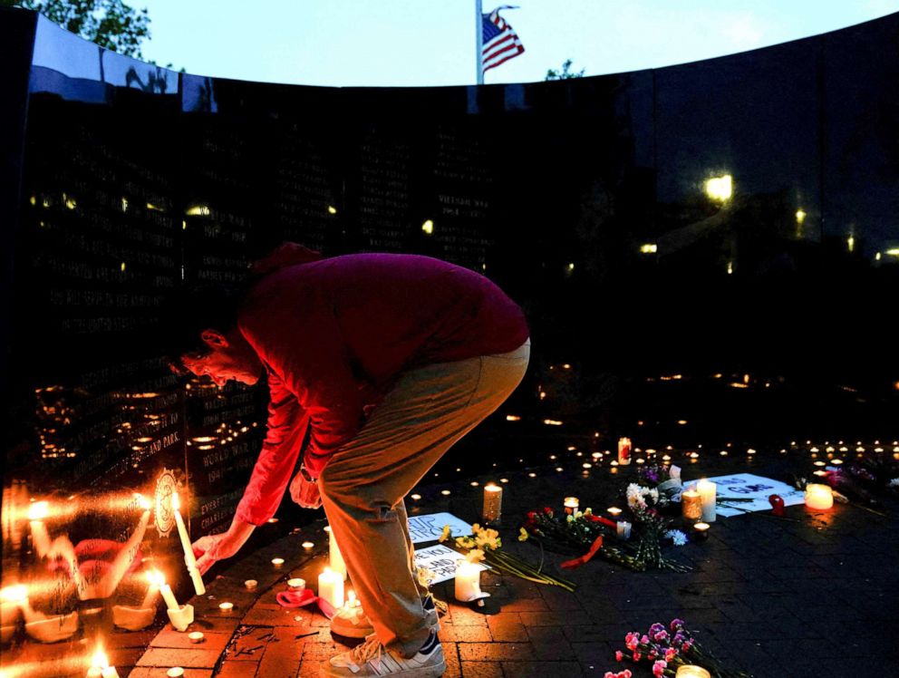 PHOTO: A community member lights a candle at a memorial site near the parade route the day after a mass shooting at a Fourth of July parade in the Chicago suburb of Highland Park, Ill., July 5, 2022. 