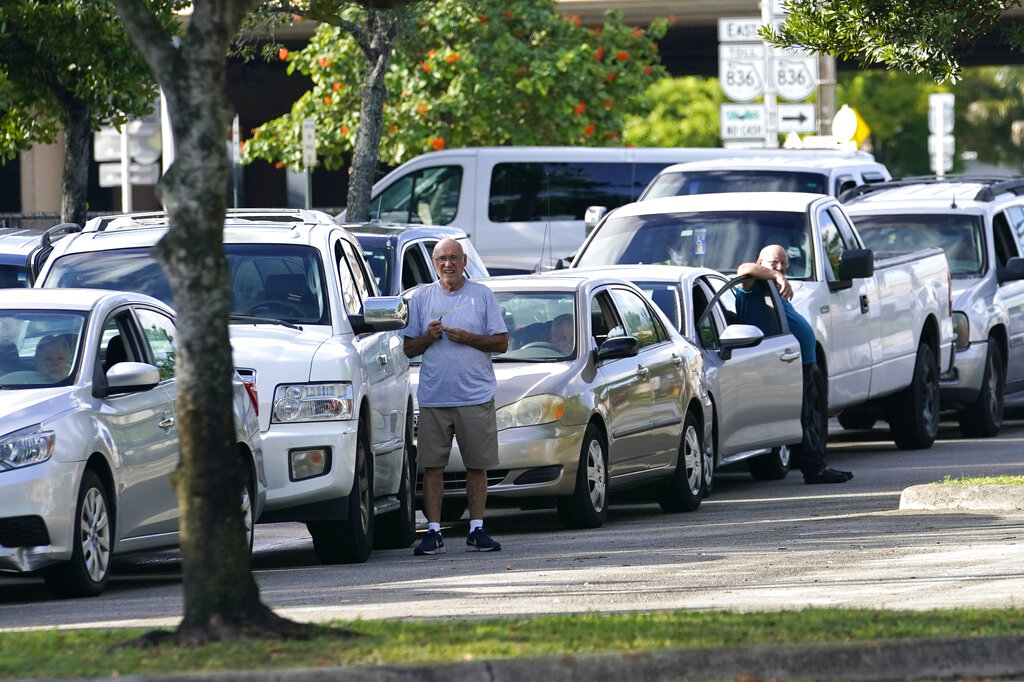 People stand outside of their vehicles as they wait in line at a food distribution held by the Farm Share food bank, Wednesday, July 20, 2022, in Miami. Long lines are back at food banks around the U.S. as working Americans overwhelmed by inflation turn to handouts to help feed their families. (AP Photo/Lynne Sladky)
