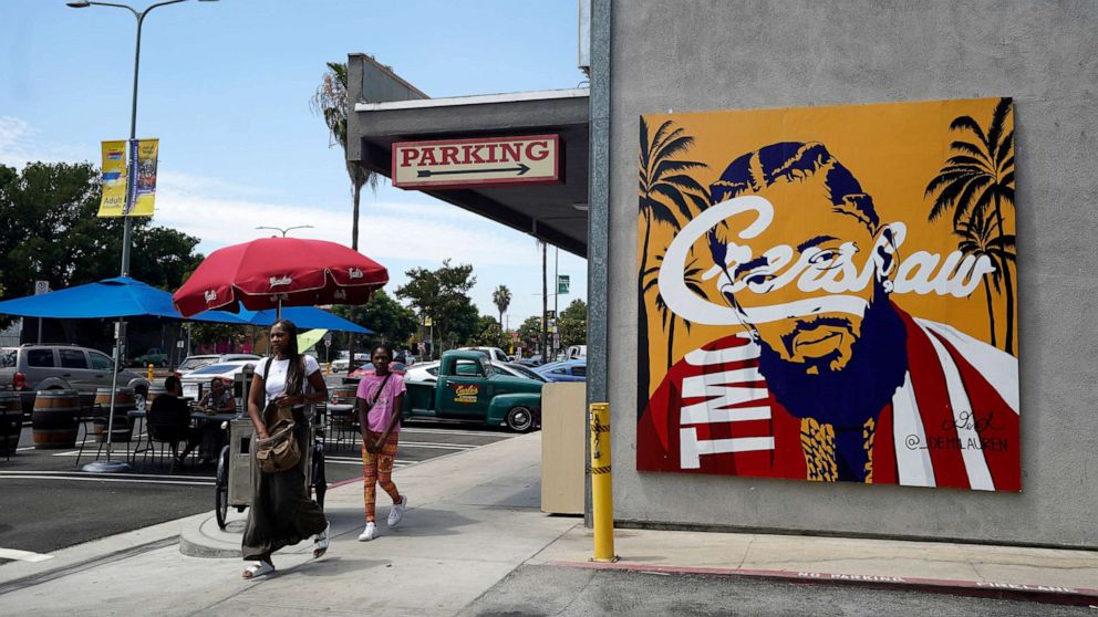 PHOTO: Pedestrians walk past a street mural of the late rapper Nipsey Hussle, June 30, 2022, in the Crenshaw district of Los Angeles.