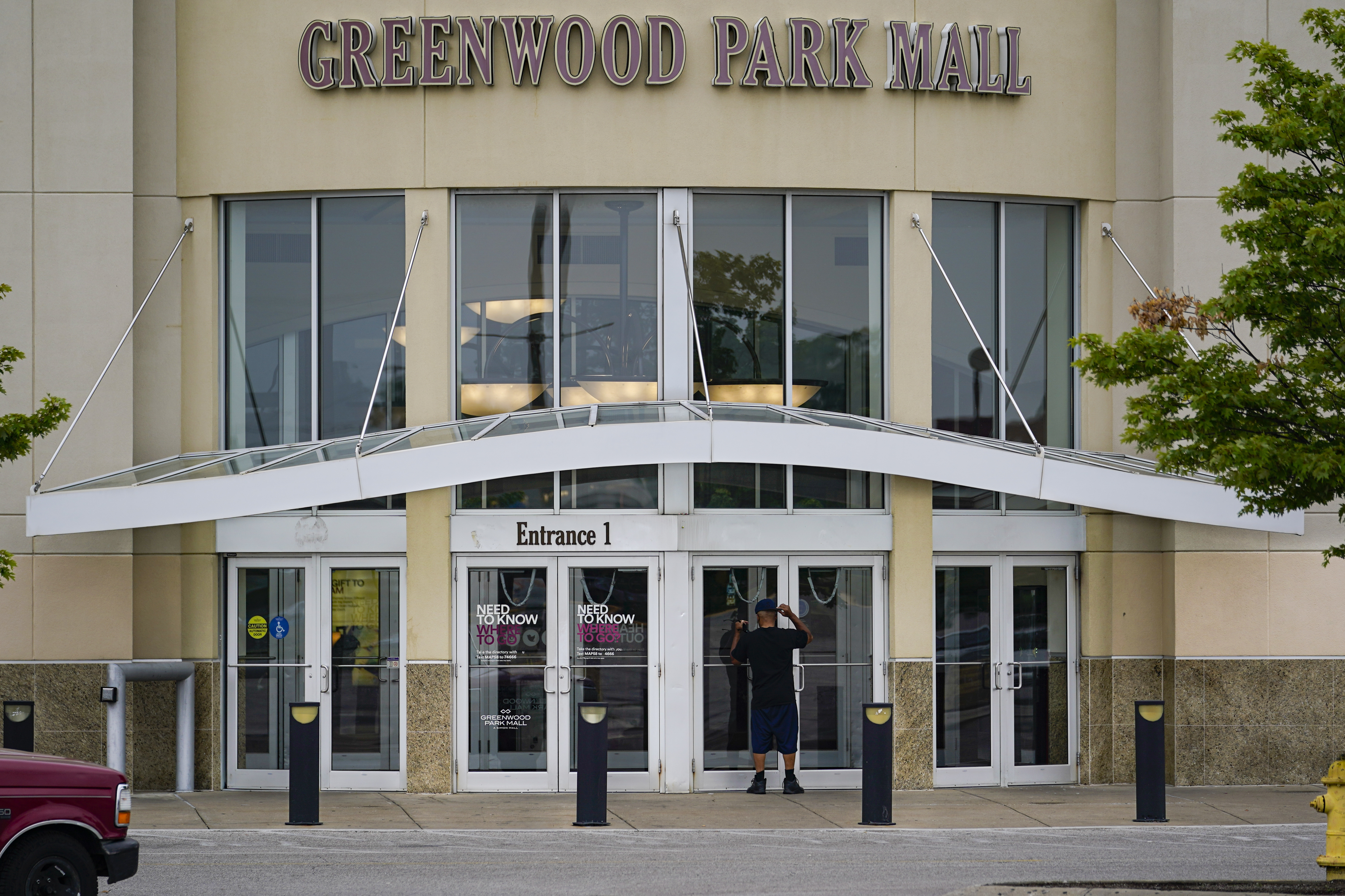 A customer checks a door on the closed Greenwood Park Mall in Greenwood, Ind., Monday, July 18, 2022. The mall was closed Monday after police say three people were fatally shot and two were injured, including a 12-year-old girl, after a man with a rifle opened fire in a food court and an armed civilian shot and killed him. (AP Photo/Michael Conroy)