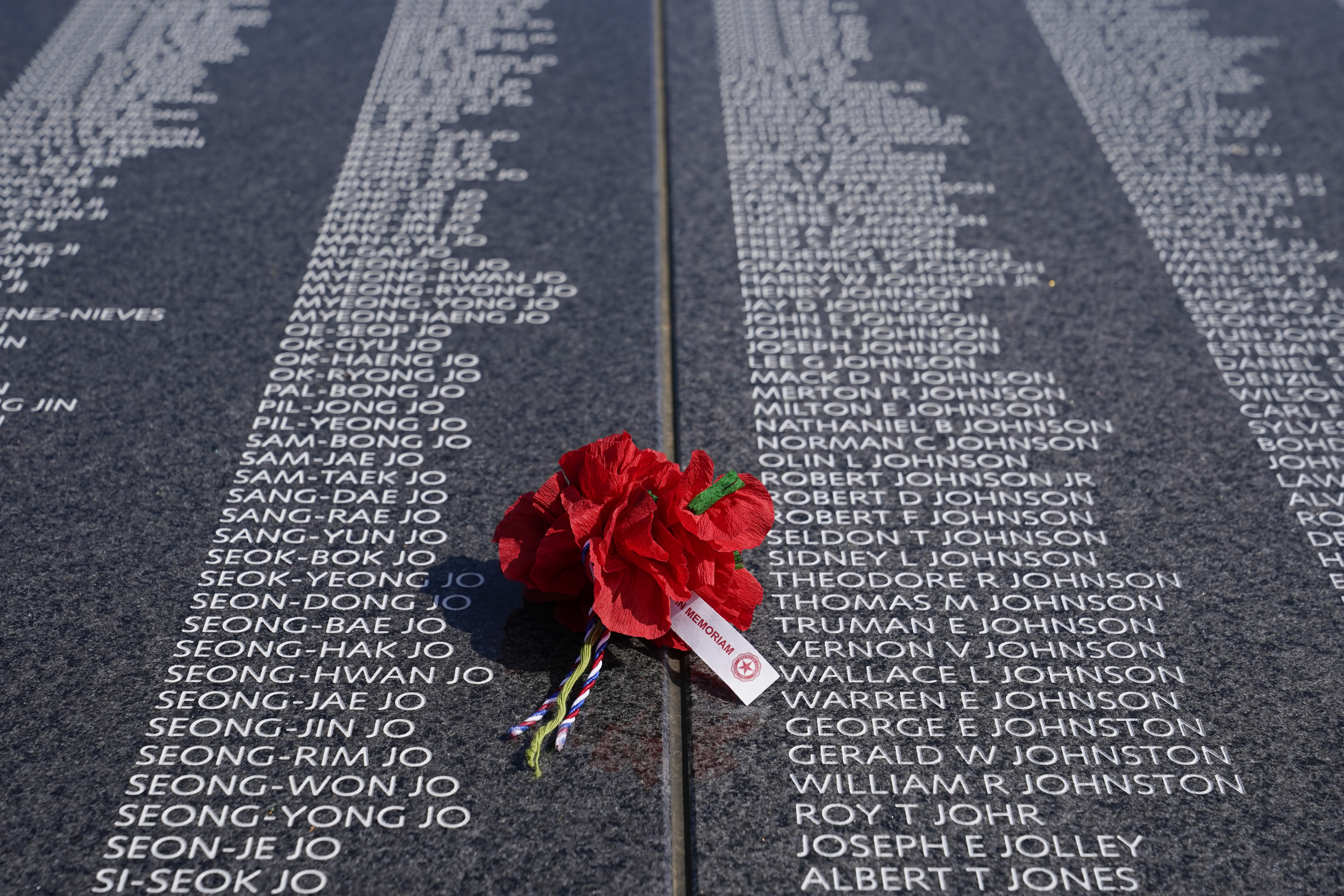 A bouquet rests on a section of the Korean War Veterans Memorial's newly unveiled Wall of Remembrance, Wednesday, July 27, 2022, in Washington. (AP Photo/Patrick Semansky)