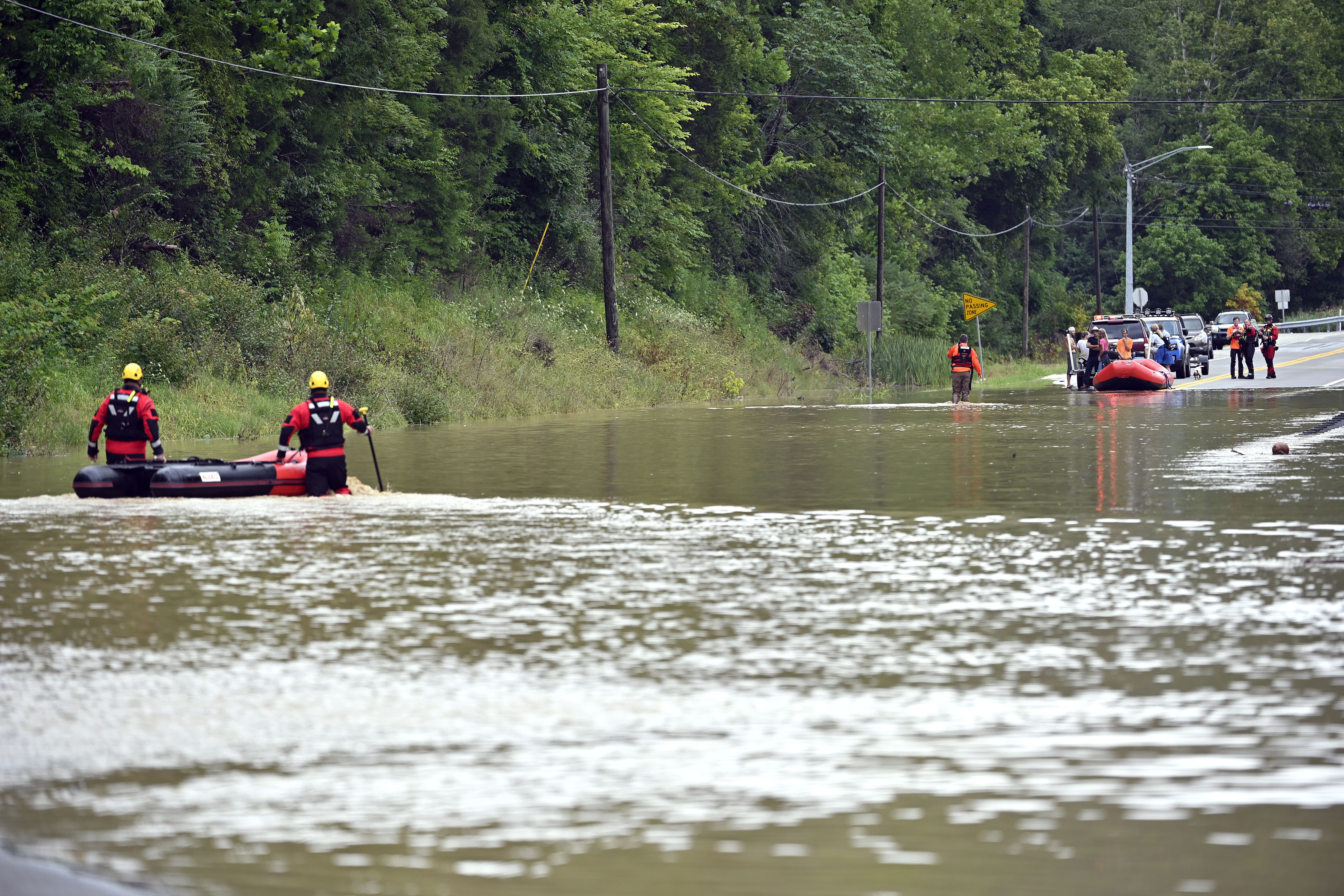 Members of the Winchester, Ky., Fire Department walk inflatable boats across flood waters over Ky. State Road 15 in Jackson, Ky., to pick up people stranded by the floodwaters Thursday, July 28, 2022. (AP Photo/Timothy D. Easley)