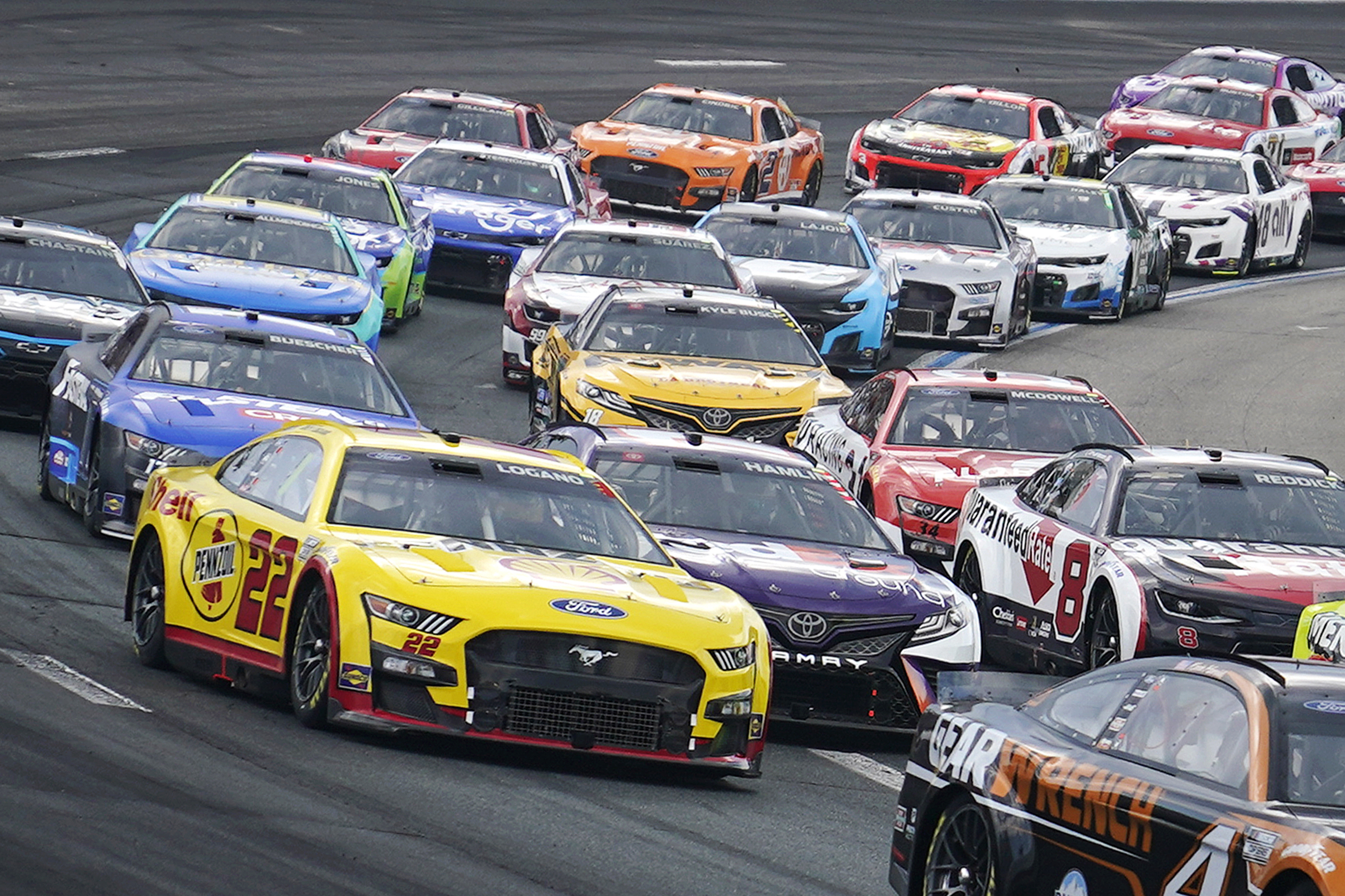 A tight pack of cars enters Turn 2 during a NASCAR Cup Series auto race at the New Hampshire Motor Speedway, Sunday, July 17, 2022, in Loudon, N.H. (AP Photo/Charles Krupa)