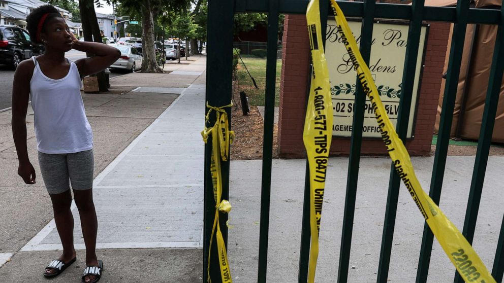 PHOTO: A woman pauses on a sidewalk, where according to police reports a shooting killed one man and injured another on Wednesday night outside an apartment building in the South Jamaica section of Queens, New York, July 7, 2022. 