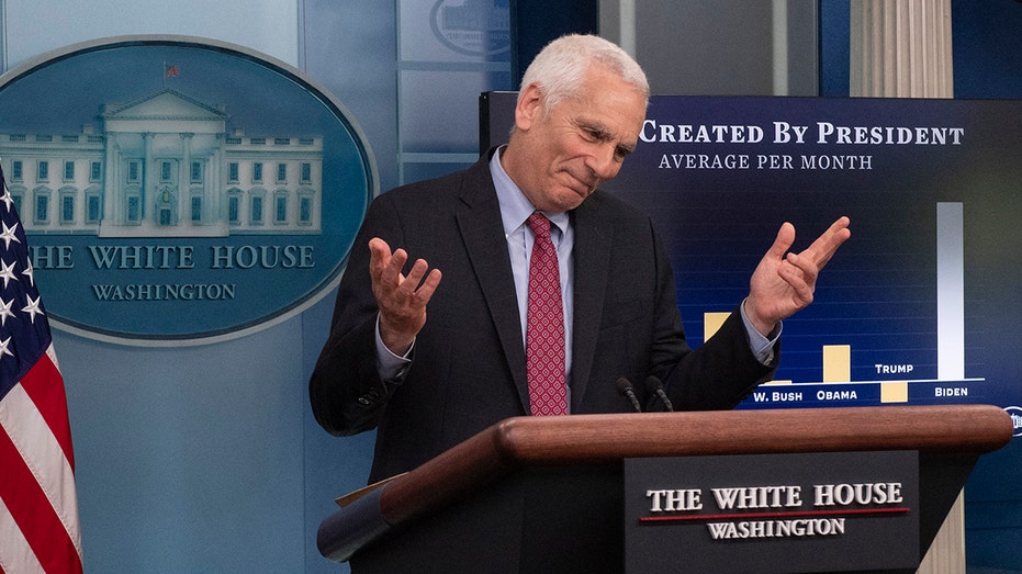 White House economic adviser Jared Bernstein shrugs in a suit in front of the White House logo