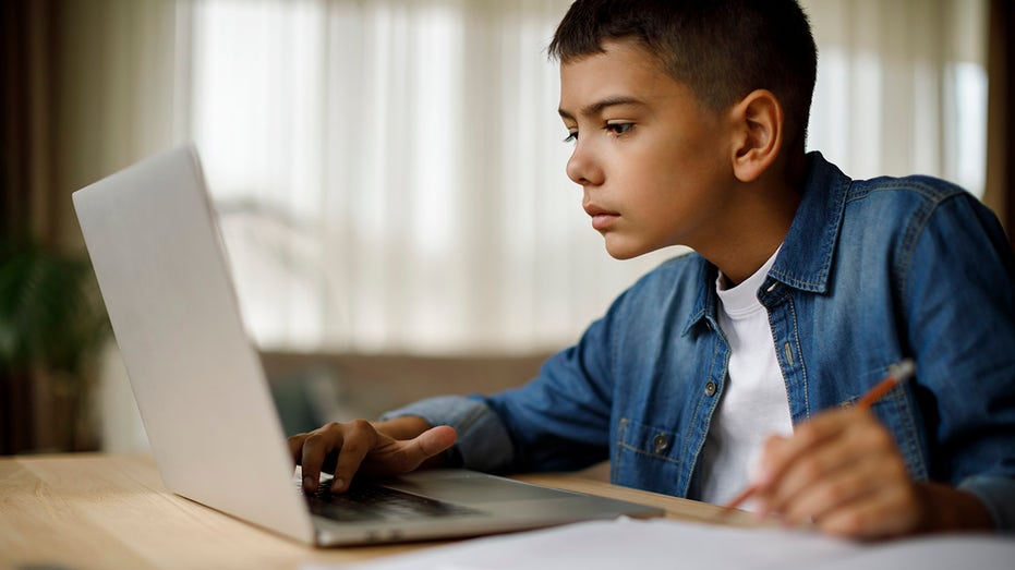 kid does homework on laptop