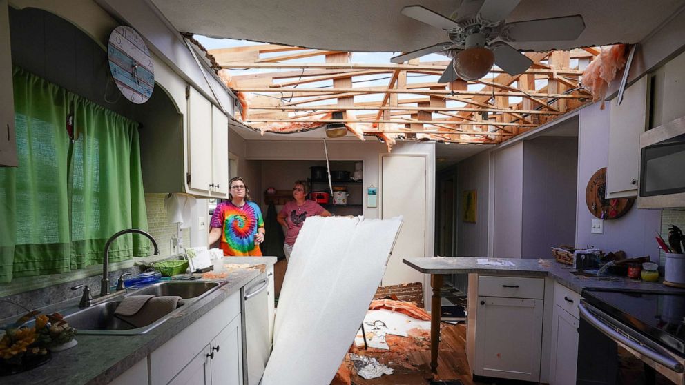 PHOTO: Andrea Barrios and her daughter Hannah look over the damaged home of her father in an effort to salvage personal belongings in the aftermath of Hurricane Ian in Charlotte Harbor, Fla., Sept. 29, 2022.