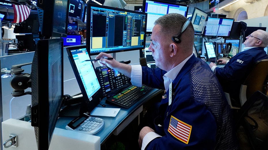 Trader Justin Flinn, left, works on the floor of the New York Stock Exchange, Wednesday, March 16, 2022. (AP Photo/Richard Drew)