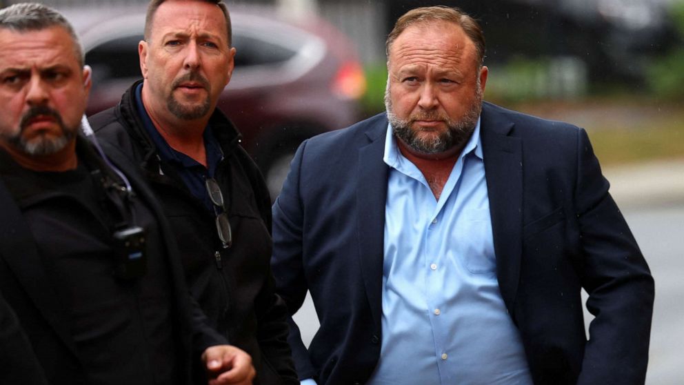 PHOTO: Infowars founder Alex Jones arrives with private security guards to speak to the media after appearing at his Sandy Hook defamation trial at Connecticut Superior Court in Waterbury, Conn. Oct. 4, 2022.