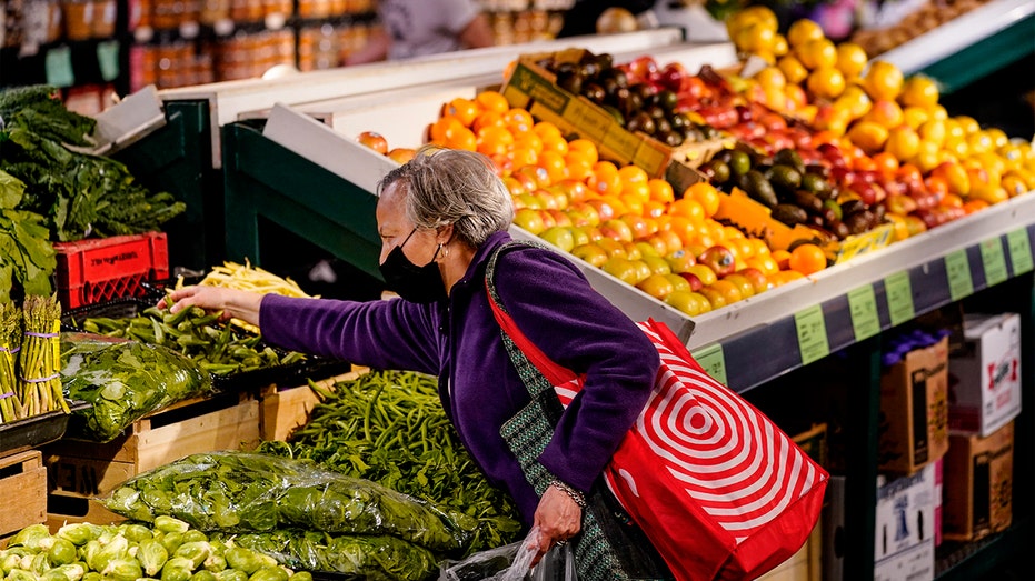 A hopper wearing a protective mask as a precaution against the spread of the coronavirus selects produce at the Reading Terminal Market in Philadelphia, Friday, April 22, 2022. (AP Photo/Matt Rourke)