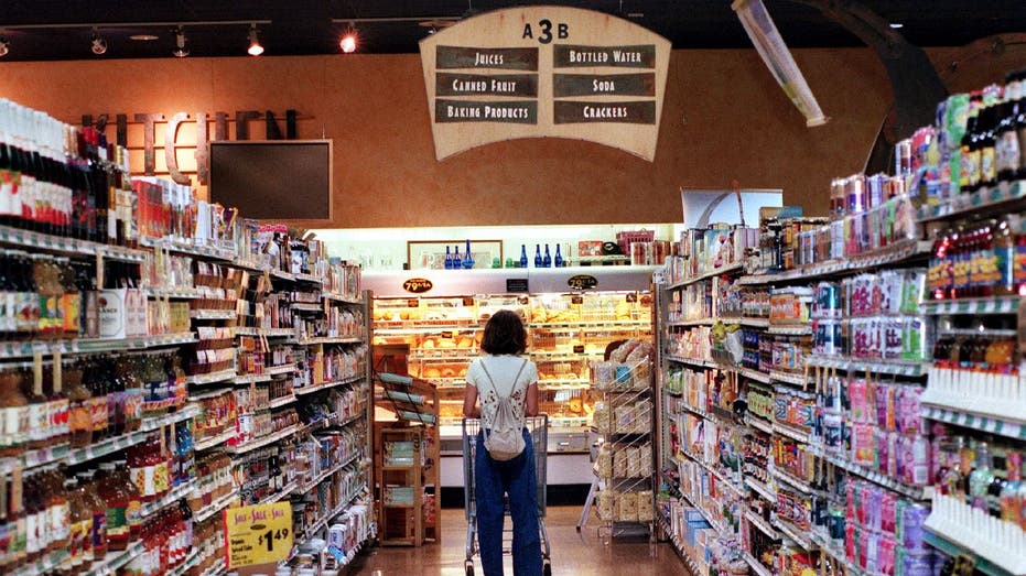 Woman pushes grocery cart down an aisle