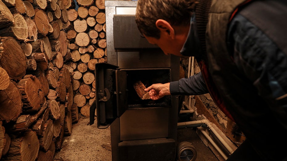 Man puts firewood into fireplace