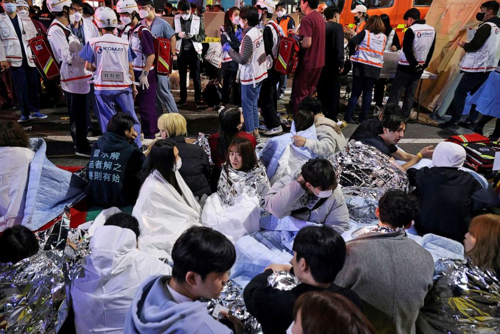 PHOTO: People sit on the street after being rescued, at the scene where dozens of people were injured in a stampede during a Halloween festival in Seoul, South Korea, Oct. 30, 2022.