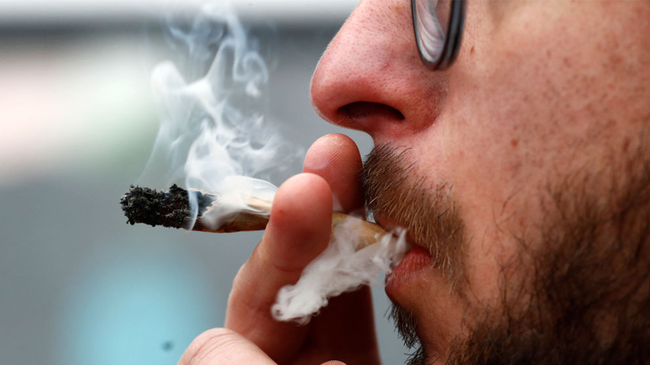 A man with a beard smoking a joint