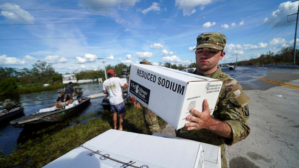 PHOTO: A member of the Florida National Guard helps stack emergency supplies that arrived by boat during flooding along the Peace River in the aftermath of Hurricane Ian in Arcadia, Fla., Oct. 3, 2022.