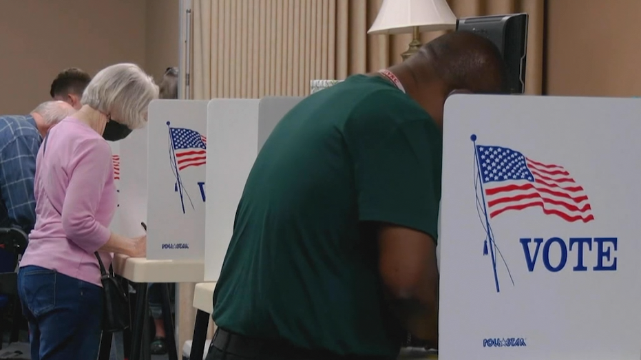 A male and female voter casting their vote at the ballot box