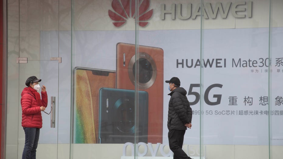 Man walking outside with giant Huawei ads