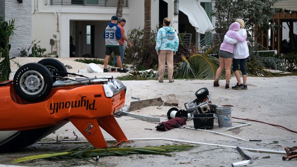 PHOTO: People embrace as they survey property damage from Hurricane Ian, Sept. 29, 2022, in Bonita Springs, Fla.