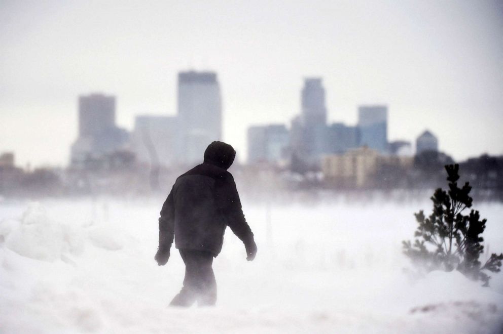 PHOTO: A man goes for a walk in front of the Minneapolis skyline at Bde Maka Ska Park during a snowstorm in Minneapolis, Feb. 22, 2023.