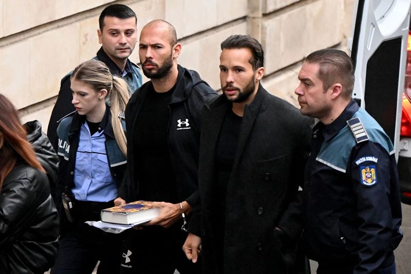 British-US former professional kickboxer and controversial influencer Andrew Tate (3rd R) and his brother Tristan Tate (2nd R) arrive handcuffed and escorted by police at a courthouse in Bucharest on January 10, 2023 for a court hearing on their appeal against pre-trial detention for alleged human trafficking, rape and forming a criminal group. (Photo by Daniel MIHAILESCU / AFP) (Photo by DANIEL MIHAILESCU/AFP via Getty Images)