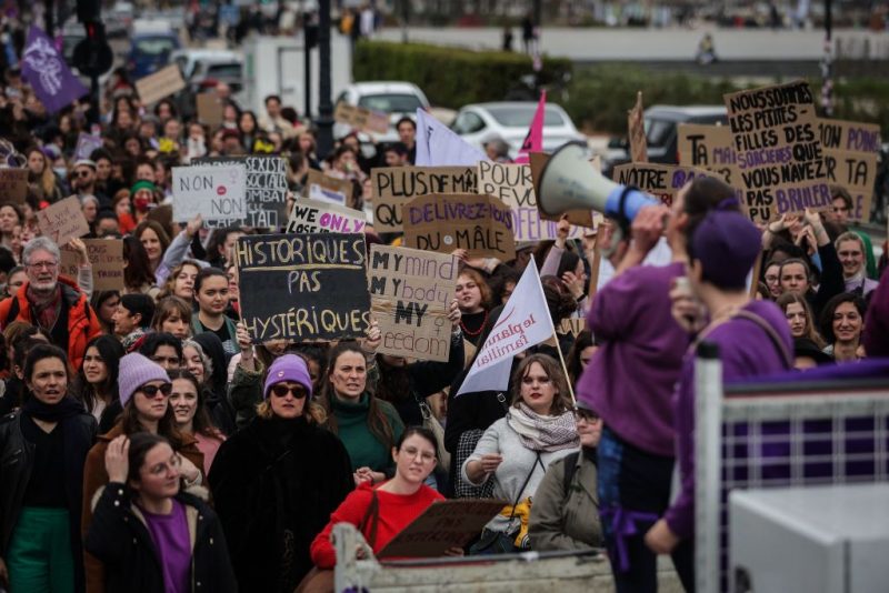 Protesters hold signs reading during a rally to mark the International Women's Day in Bordeaux, on March 8, 2023, one day after the nationwide rallies organized since the start of the year against French President's pension reform and its postponement of the legal retirement age from 62 to 64. (Photo by THIBAUD MORITZ / AFP) (Photo by THIBAUD MORITZ/AFP via Getty Images)