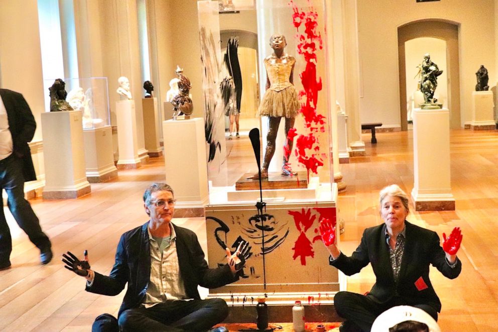 PHOTO: Declare Emergency protesters sit on the floor after smearing paint on the case and pedestal of Edgar Degas's "Little Dancer Aged Fourteen" sculpture in the National Gallery of Art in Washington, Apr, 27, 2023.