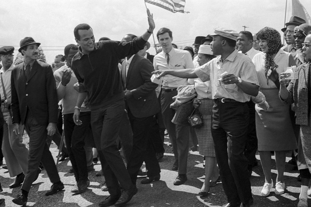 PHOTO: Singer Harry Belafonte waves to Dr. Martin Luther King, Jr., right, as he leaves the column of civil rights marchers after walking with them in Montgomery, Ala., March 24, 1965.