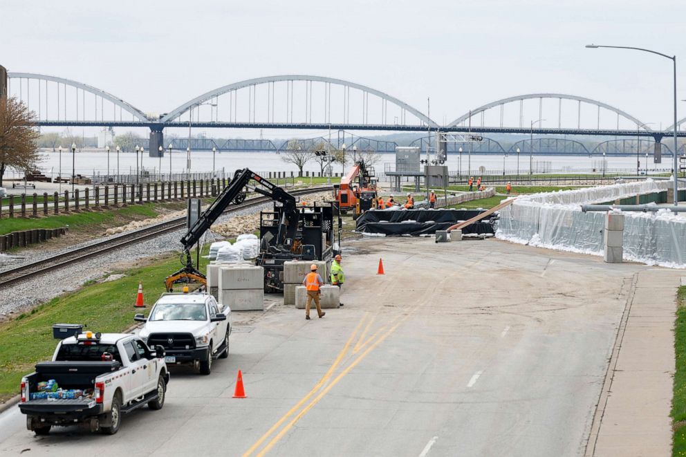 PHOTO: HESCO sand barriers are installed at right as Canadian Pacific workers, left, install barriers along River Drive and their downtown Davenport, Iowa rail line, April 24, 2023, Davenport, Iowa.