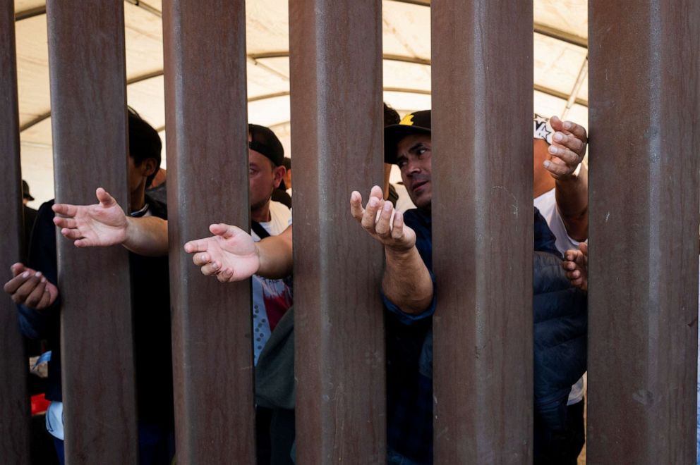 PHOTO: Migrants reach for water through the Mexico - U.S. border wall in San Luis Rio Colorado in Mexico, before the lifting of Title 42, as seen from San Luis, Arizona, U.S., May 11, 2023.