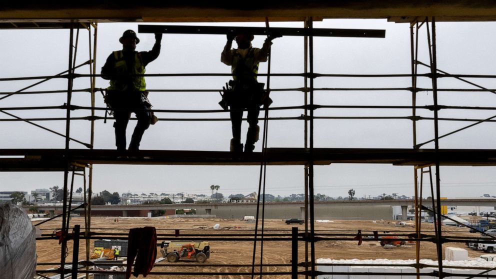 PHOTO: Construction workers work on scaffolding overlooking three new grass practice fields under construction at the Los Angeles Chargers new 145,000 square feet headquarters and practice facility on May 18, 2023 in El Segundo, California.