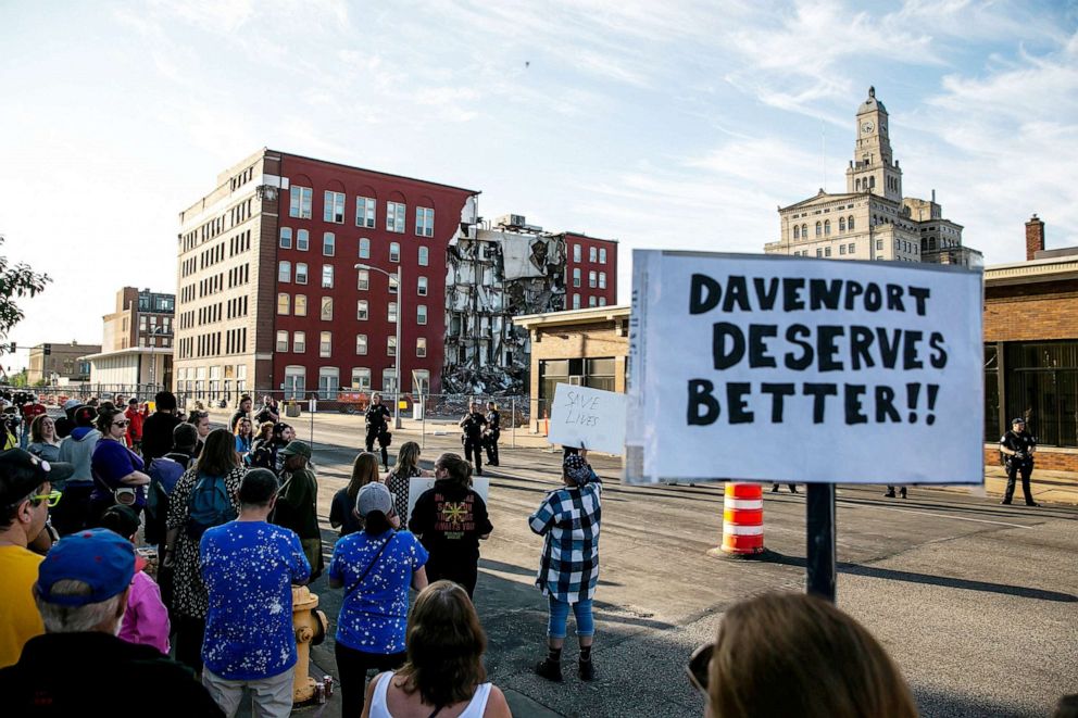 PHOTO: Davenport police officers form a line opposite protesters that are advocating for search efforts to continue near the site of an apartment building that partially collapsed in Davenport, Iowa, May 30, 2023.