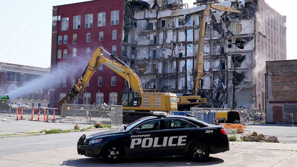 PHOTO: A police officer watches the start of the demolition of the partially collapsed apartment building, June 12, 2023, in Davenport, Iowa.