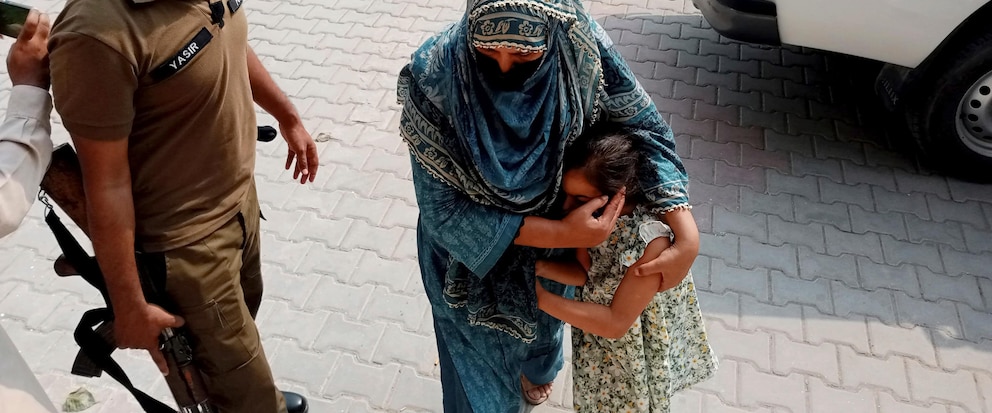 Police officers escort a relative and a child of a couple wanted by British police in connection with last month's death of the couple's young daughter on the outskirts of London, to appear in a court in Jhelum, Pakistan, about 175 kilometres (110 miles) northwest of Lahore, Tuesday, Sept. 12, 2023. Sara Sharif, 10, was found dead at her British home on Aug. 10. A Pakistani court ordered her five siblings put in the custody of a children's protection center. The police are continuing their search for the girl’s father and stepmother. (AP Photo/Tahir Mahmood)