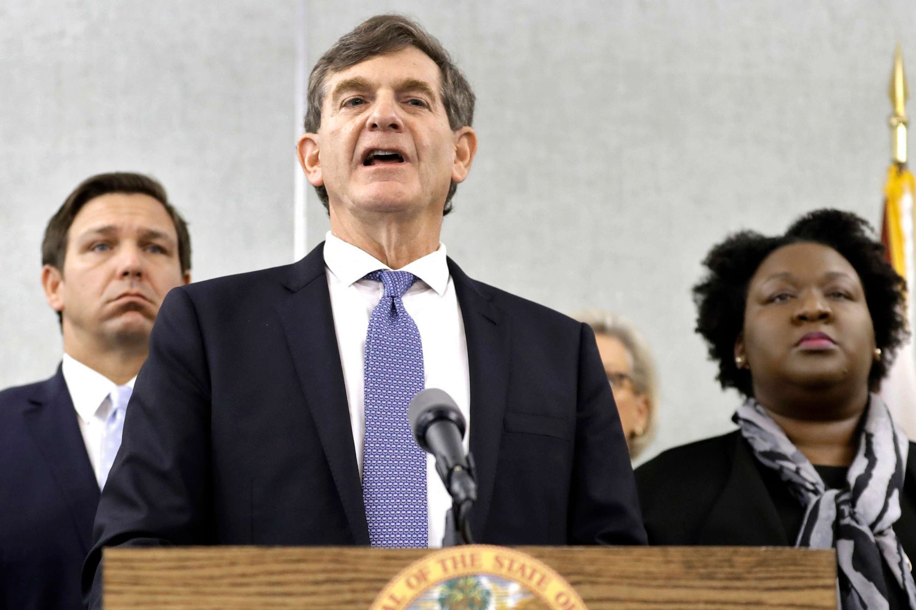 PHOTO: Dr. Scott Rivkees speaks to the media as he is flanked by, Gov. Ron DeSantis, left, and Deputy Secretary for Health Dr. Shamarial Roberson, right, March 2, 2020, in Tampa.