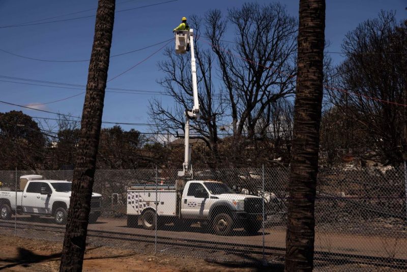 A Hawaiian Electric employee repairs power lines in the aftermath of the Maui Fires in Lahaina, West Maui, Hawaii, August 17, 2023. Embattled officials in Hawaii who have been criticized for the lack of warnings as a deadly wildfire ripped through a town insisted on August 16 that sounding emergency sirens would not have saved lives. At least 110 people died when the inferno levelled Lahaina last week on the island of Maui, with some residents not aware their town was at risk until they saw flames for themselves. (Photo by Yuki IWAMURA / AFP) (Photo by YUKI IWAMURA/AFP via Getty Images)