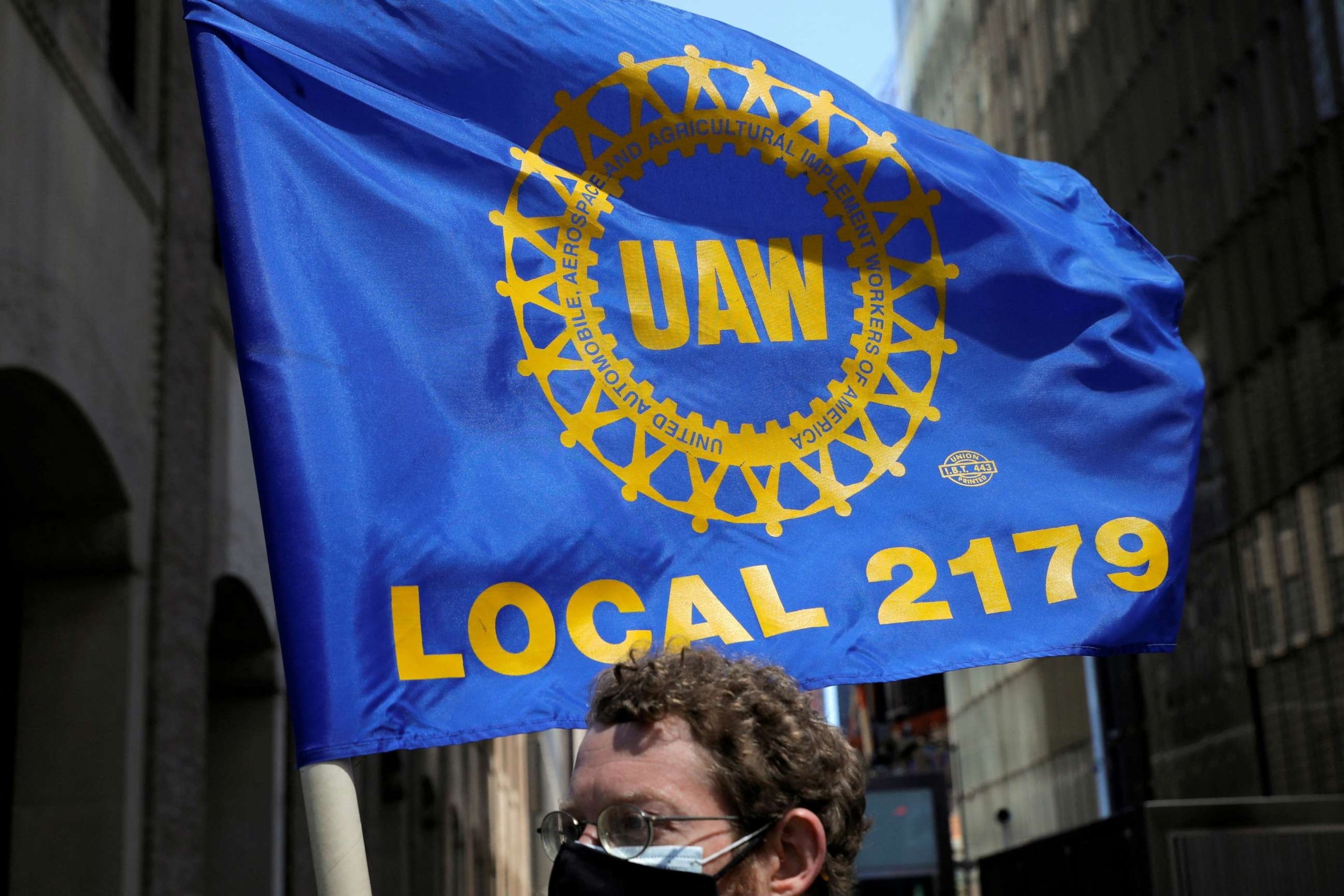 PHOTO: A person carries a flag with the patch from the United Auto Workers (UAW) labor union during a May Day rally for media workers held by The NewsGuild of New York on International Workers' Day in Manhattan, New York City, May 1, 2021.