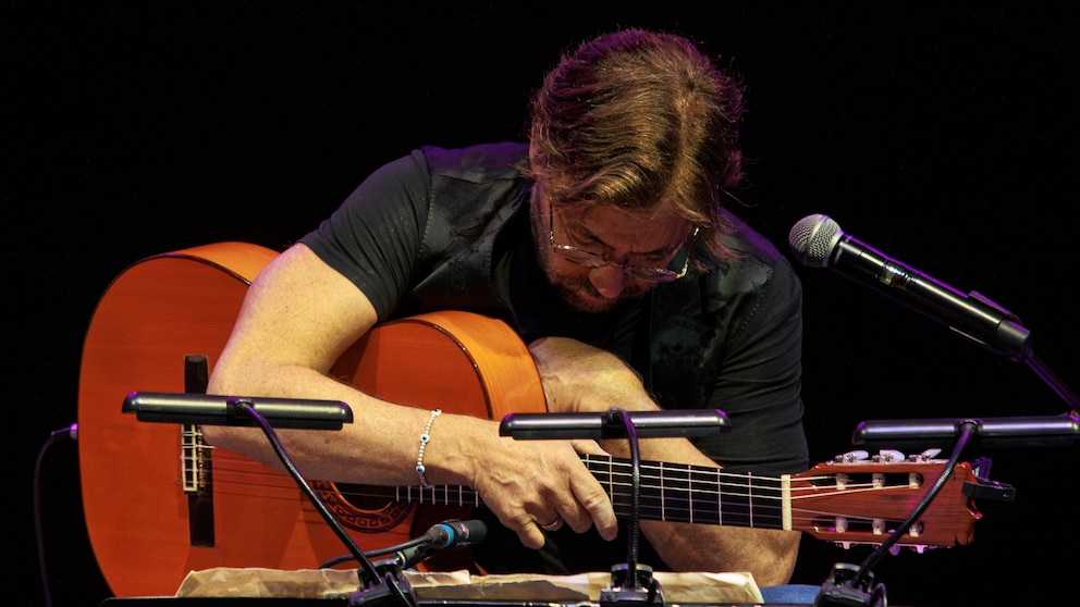 U.S. guitarist Al Di Meola clutches his chest shortly before struggling to walk off the stage at the Arenele Romane concert venue during his performance in Bucharest, Romania, Wednesday evening, Sept. 27, 2023. Di Meola suffered a heart attack during a performance in Romania’s capital but is currently in a stable condition and receiving treatment, a hospital spokesperson said on Thursday. (AP Photo/Dragos Cristescu)