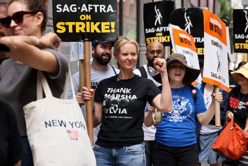 NEW YORK, NEW YORK - JULY 21: Cynthia Nixon (C) joins SAG-AFTRA members on the picket line outside of Netflix and Warner Bros on July 21, 2023 in New York City. Members of SAG-AFTRA, Hollywood's largest union which represents actors and other media professionals, have joined striking WGA (Writers Guild of America) workers in the first joint walkout against the studios since 1960. The strike could shut down Hollywood productions completely with writers in the third month of their strike against the Hollywood studios. (Photo by Dia Dipasupil/Getty Images)