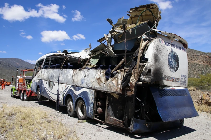 | A crashed bus sits attached to a tow truck the side of the road near Villa de Tepelmeme, Oaxaca state, Mexico, Friday, Oct. 6, 2023. At least 18 migrants from Venezuela and Peru died early Friday in the bus crash, authorities said. (AP Photo/Nemesio Mendez Jiménez)