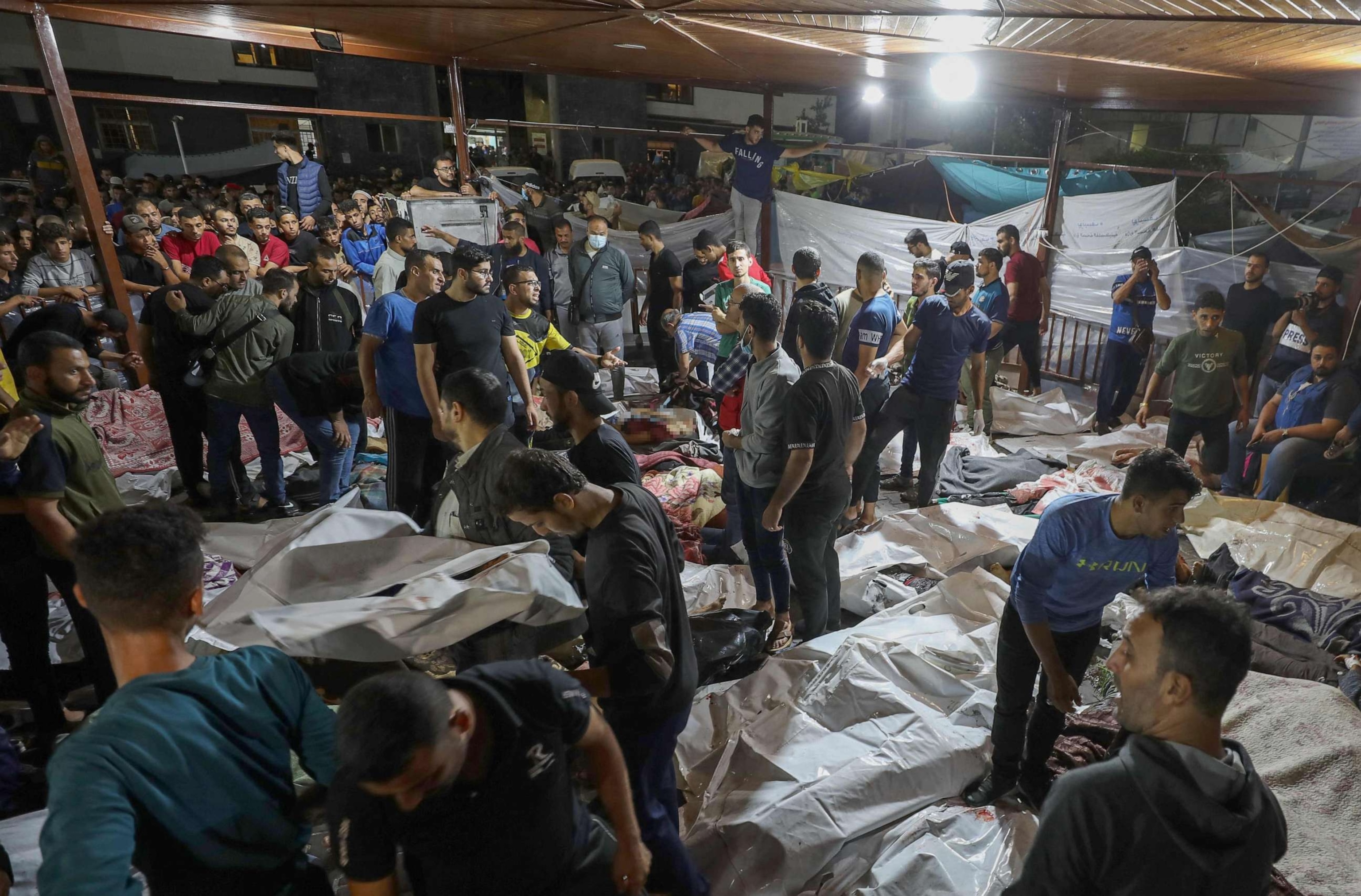 PHOTO: People gather around bodies of Palestinians killed in an airstrike on the Ahli Arab hospital in central Gaza after they were transported to Al-Shifa hospital, October 17, 2023.